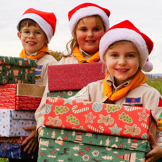Drei Pfadfinder halten Päckchen in der Hand Die Wölflinge haben Weihnachtsgeschenke gepackt