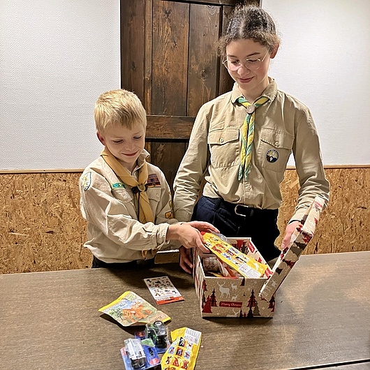 Zwei Pfadfinder packen ein Päckchen Gemeinsam werden in der Gruppenstunde die Kartons gepackt